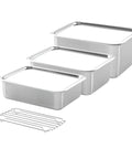 Set of stainless steel kitchen containers with a wire rack on a white background