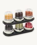 Spice rack with six transparent containers holding different spices on a white background