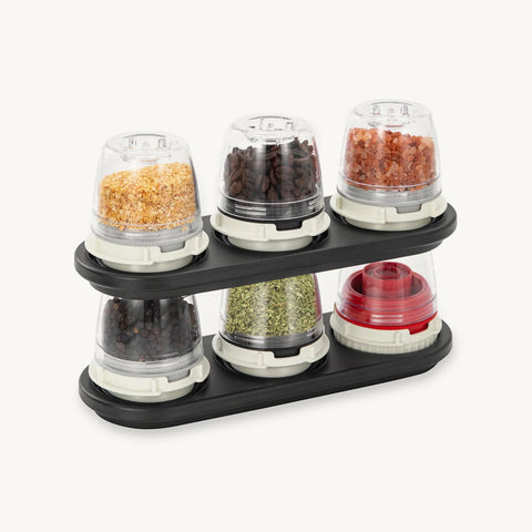 Spice rack with six transparent containers holding different spices on a white background
