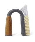 U-shaped cleaning brush with wooden handle and gray and beige bristles on a white background