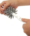 Person holding a white bottle brush with gray bristles on a white background