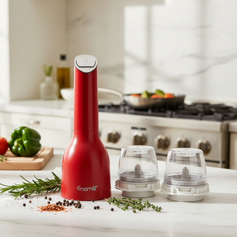 Red pepper grinder with two clear grinding chambers on a kitchen counter.