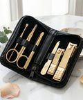 Gold manicure set in a black case on a marble surface with decorative elements.