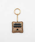 A square embroidered keychain charm featuring a brown and beige depiction of Sungnyemun gate, with a gold-tone split ring and chain, on a plain white background.