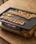 Portable grill with food on a wooden table