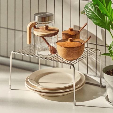 Kitchen setup with glass carafe, wooden containers, and plates on a metal rack.