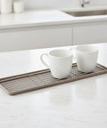 Two white mugs on a metal and silicone cup tray with a white background