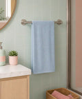 Bathroom with a light blue towel hanging on a rack, a pink cabinet, and a green plant.