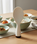 White rice paddle on a table with bowls of food