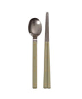 Stainless steel spoon and chopsticks with green handles on a white background