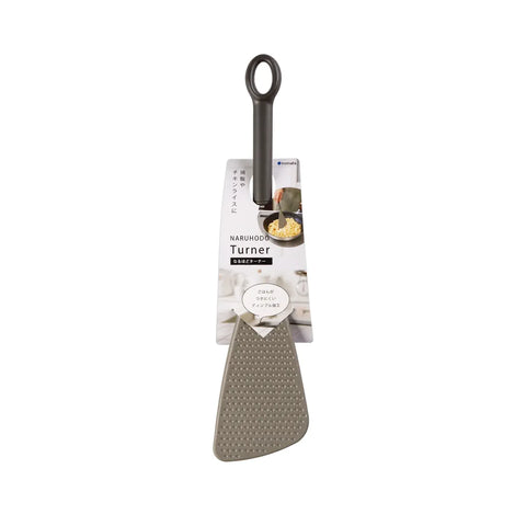 A metal turner spatula with a dark gray handle and a textured silver-gray blade, shown hanging from its retail packaging card against a plain white background.