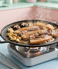 Grill pan with meat and vegetables on a portable stove in a kitchen setting