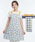 Woman wearing a blue apron with egg pattern, next to a matching towel on a white background
