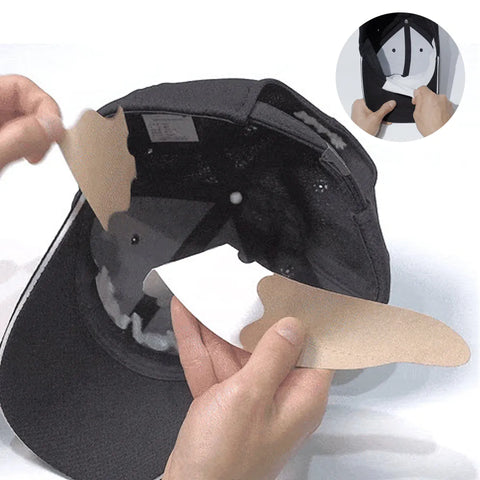 Person applying a white hat protector strip on the inside of a black cap on a white background.