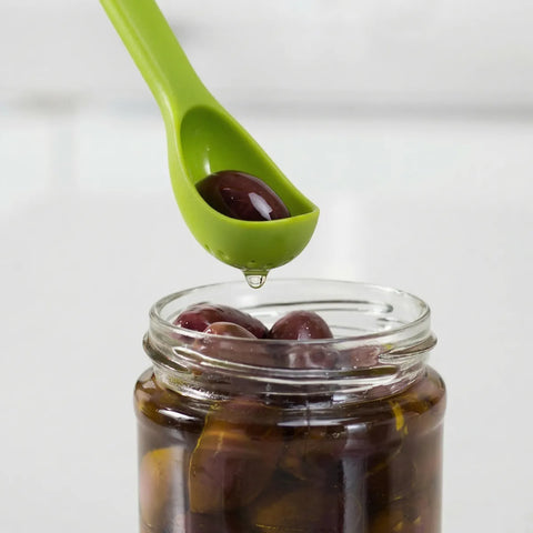 Green scoop taking an olive from a jar on a white background