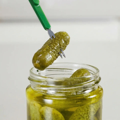 Jar of pickles with a green pickling fork lifting a pickle out.