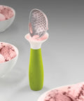 Green ice cream scoop with pink ice cream on a gray background