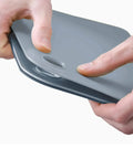 Blue and gray cutting boards held by a hand on a white background