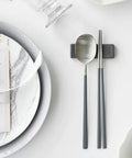 Silver spoon and chopsticks on a marble plate with a card on a white surface