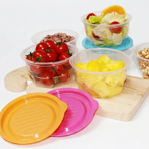 Assorted containers with fruits, vegetables, and snacks on a white background