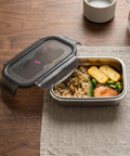 Metal lunch box with food on a wooden table