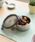 Stainless steel food container with food on a table with a plant in the background