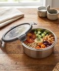 Stainless steel food container with a salad on a wooden table