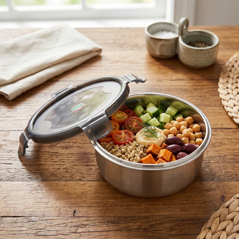 Stainless steel food container with a salad on a wooden table