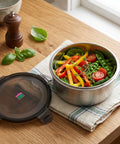 Stainless steel food container with vegetables on a wooden table