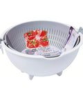 A white plastic spin wheel colander with a gray interior basket, shown on a plain white background with a tomato slice and packaged ingredients inside to demonstrate use.