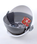 A gray and white plastic salad spinner basket with a white outer bowl and gray perforated inner basket, shown on a white background with a tomato and a circular insert visible inside.