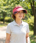 Woman wearing a pink visor in a park setting