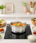 Stovetop with a pot of food surrounded by ingredients and kitchen utensils on a white countertop.