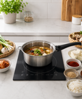 Stovetop with a pot of soup on a kitchen counter with ingredients around