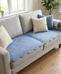 Gray sofa with a blue couch pad and pillows in a bright living room.