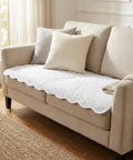 Beige sofa with decorative pillows and a blanket in a bright room.