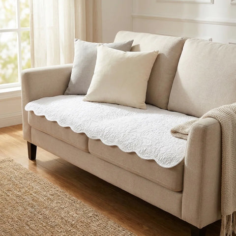 Beige sofa with decorative pillows and a blanket in a bright room.