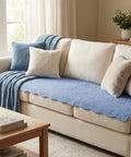 Beige sofa with blue couch pad and pillows in a living room setting.