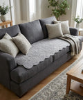Gray sofa with decorative pillows and gray couch pad in a living room setting.