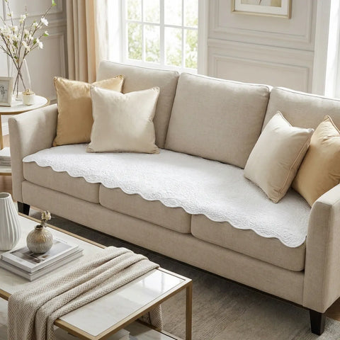 Beige sofa with white couch pad and decorative pillows in a living room setting