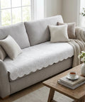 Light gray sofa with white couch pad and decorative pillows and a blanket in a bright living room.