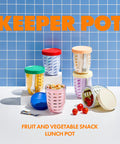 Colorful 'KEEPER POT' containers on a blue tiled background with text indicating they are for fruit and vegetable snacks.