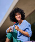Woman holding a food container cup with a fork outdoors
