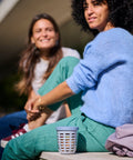 Two women sitting outdoors with a food container cup between them