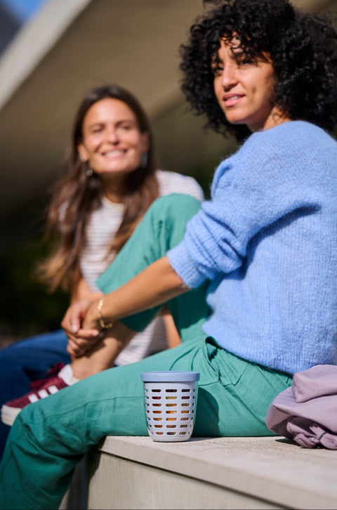 Two women sitting outdoors with a food container cup between them