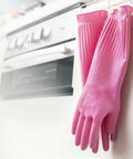 Pink rubber gloves hanging on a rack in a kitchen.