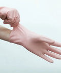 Pink rubber glove being put on a hand against a light gray background