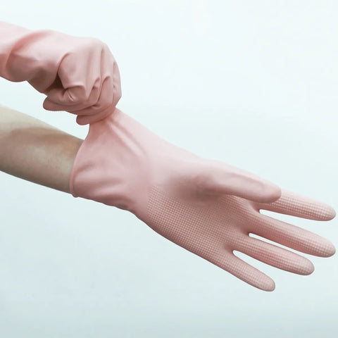 Pink rubber glove being put on a hand against a light gray background