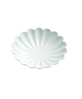 A white ceramic scalloped plate with a delicate petal or shell-like edge, shown from a top-down view on a solid white background.