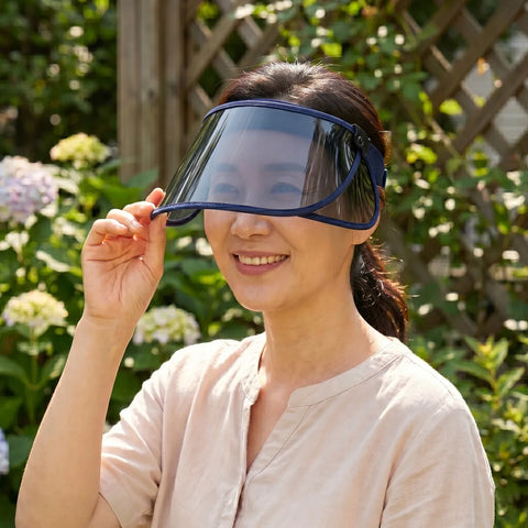 Woman holding a visor outdoors with greenery in the background